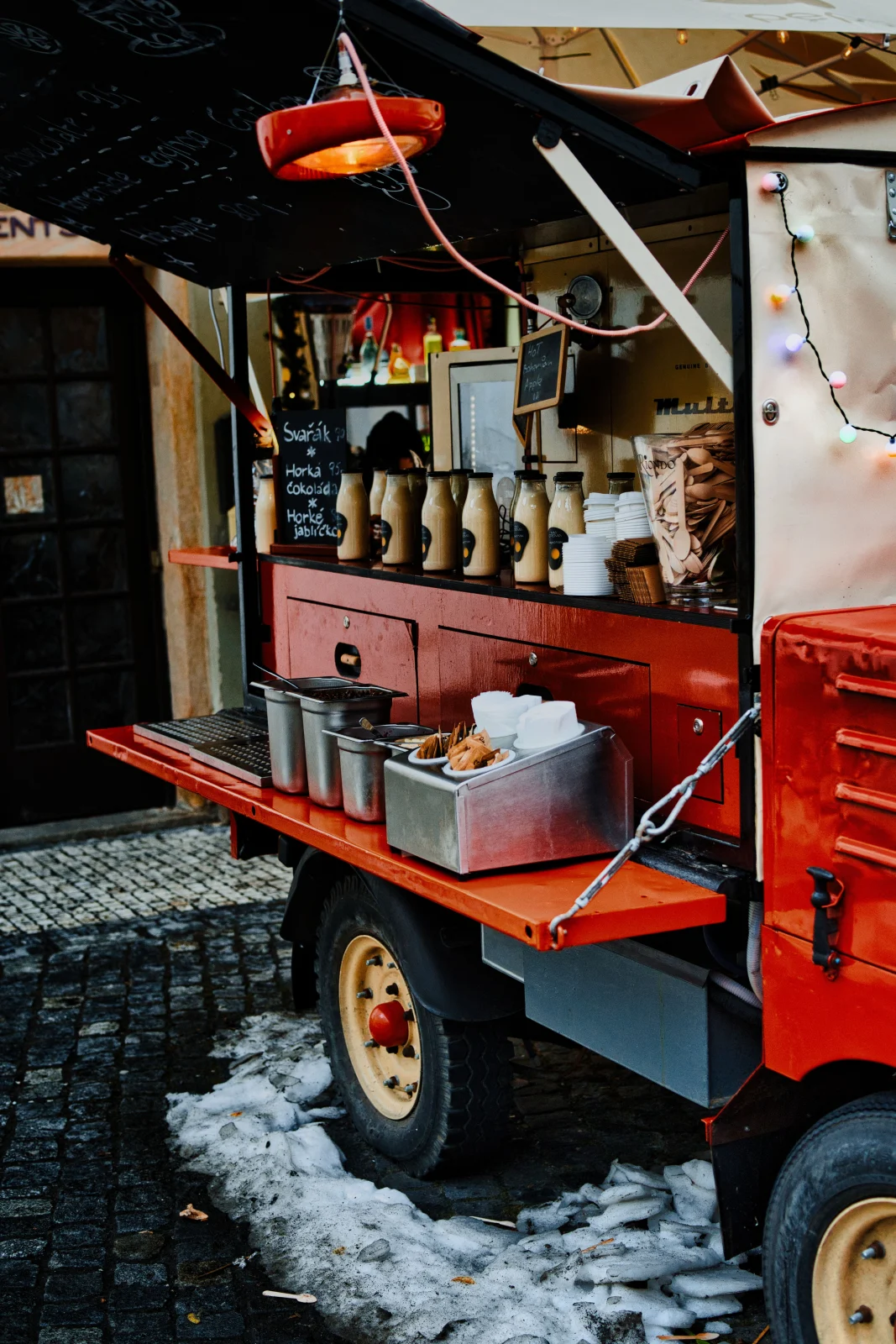 A red food truck open for service on a cobblestone street