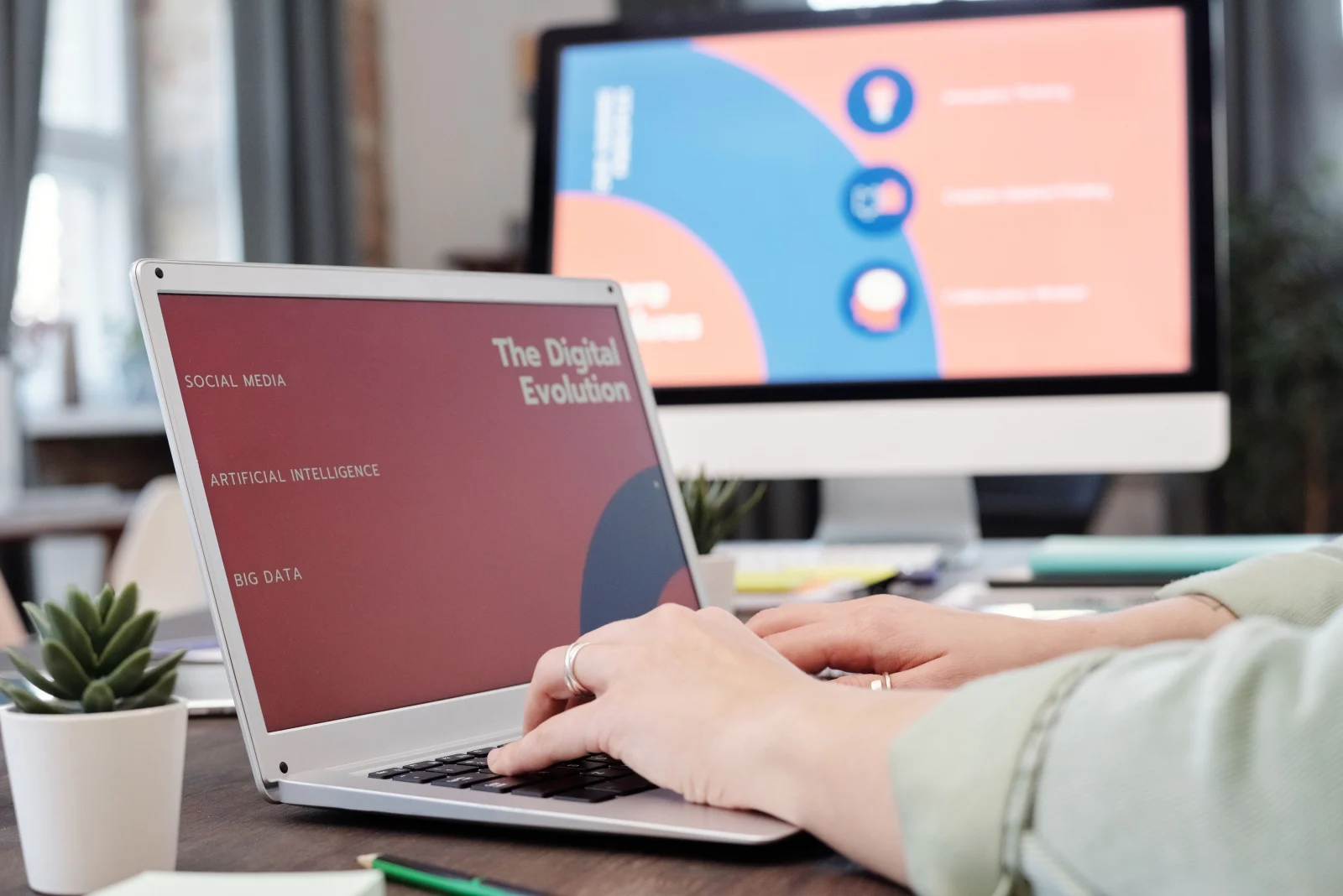 A laptop and monitor showing slide layouts in progress